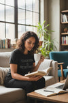Woman reading a book and holding a mug in a cozy living room.